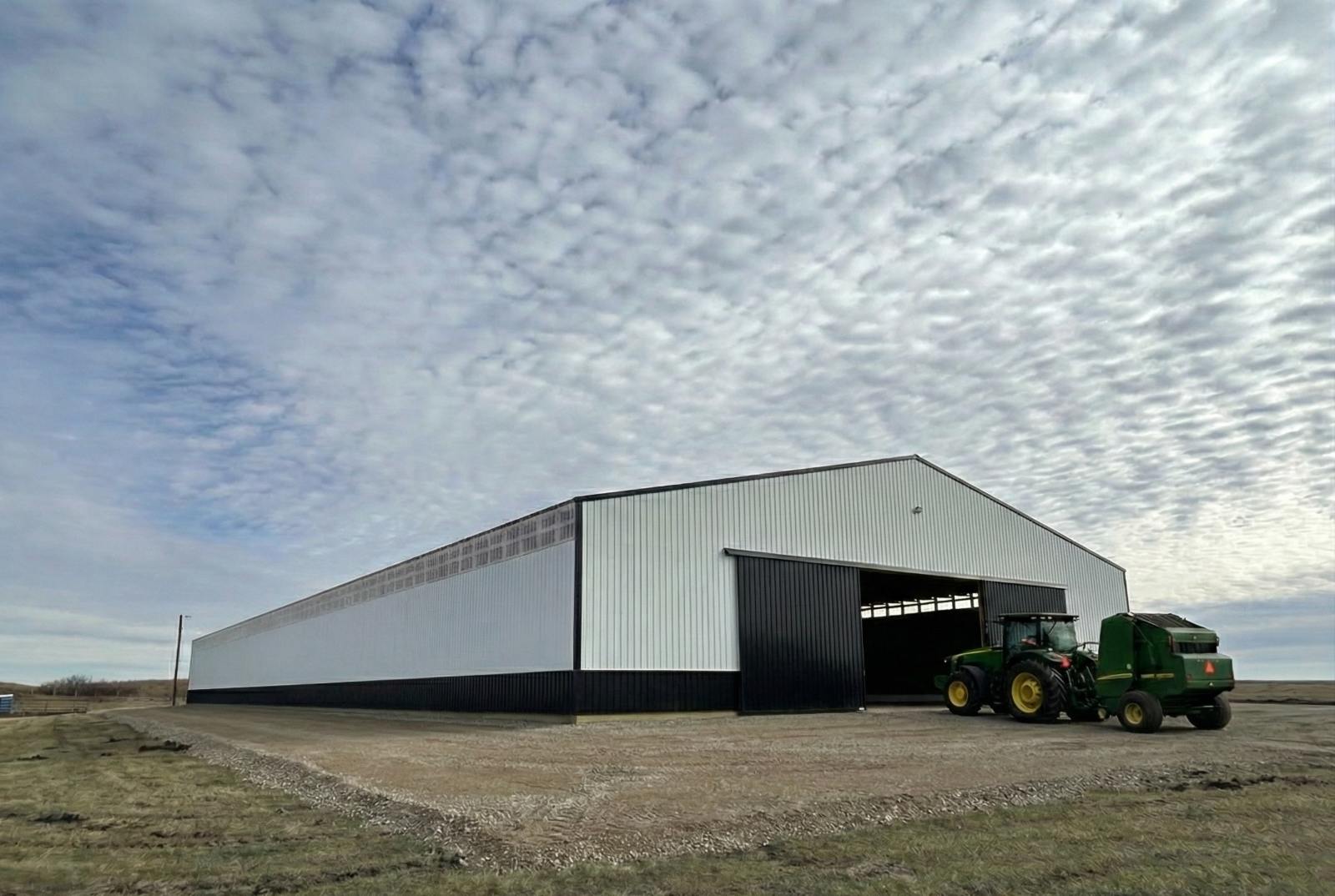 Finished equipment storage building on a farm in western North Dakota, with a tractor and baler parked at the open door.